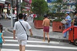 A man casually walks in the middle of a busy Shanghai street wearing nothing else than a pair of boxers and sandals.