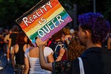 A participant holds a placard reading “Reality is Queer” during 2022 Pride month in Berlin.