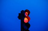 Red traffic light against blue sky.