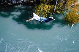 A man during a bungee jump over the river.