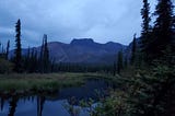 Mountain, black spruce trees surrounding small beaver lake