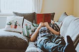 man on a sofa, reading a book