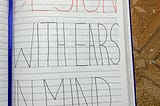 An image of an opened notebook with the words “Design with ears in mind” being held open by a pen