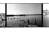 People swimming in a pink salt lake in Burgas, Bulgaria, shot on a blacka and white film roll.