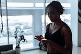 A woman in a black sports bra lighting a candle in a well-lit room