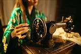 An old sewing machine, with the obscured figure of a woman operating it.