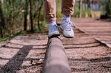 Les pieds d’une personne qui fait l’équilibre sur une poutre (de parcours santé en plein air)