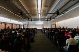 Photo of a large conference room full of people looking at the screen