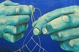 Mural painting of teal hands pulling light thread across a blue background. Mural is on wall in El Cotillo, Fuerteventura. Unknown origin. Seen March 2019