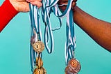 two hands holding a bunch of awards medals