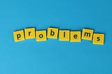 Yellow tiles on a blue background that spell “problems”.