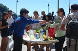 Young kids dealing with a crowd of people around their lemonade stand.