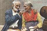 Image by Anonymous (1890s). An elderly couple sharing a tender, loving moment, with the man holding a small piece of food up to the woman’s mouth as she smiles warmly at him.