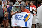 Two people with a “Families Belong Together” sign at an ACLU rally 1 June 2018