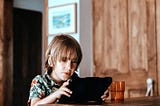 A homeschooled boy sits at home with his device. Is he getting enough socialisation?