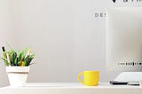 7 essential rules to design like a true professional — a desk with a computer on it and a yellow coffee cup.