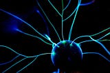 Streaks of bright blue static electricity from a metal ball on a black background