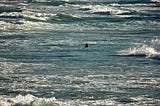 A lone person surrounded by waves in the middle of an ocean