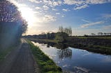 Sunlight streaming onto a canal and canal path.