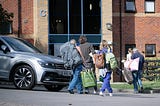 Students moving in with family members helping, carrying items from the car