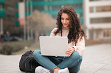 college student outside using laptop