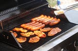 cooking sausages on a propane grill