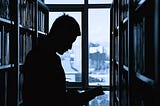 An academic readin a book in a library.