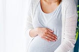 young pregnant woman holding abdomen lovingly