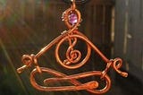Meditating figure made from copper with a crystal in the head space and a music symbol in the heart space.