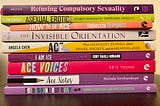 A stack of ace-themed books: Refusing Compulsory Sexuality, Asexual Erotics, How to be Ace, The Invisible Orientation, Ace: What Asexuality Reveals About Desire, Society and the Meaning of Sex, I Am Ace, Ace Voices, Ace Notes, and Sounds Fake But Okay.