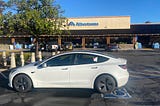 White Tesla Car in front of Grocery Store.