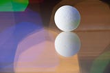 Close-up of a reflected pill on a reflective surface. Colorful lights background.