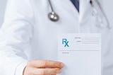 Person in white coat holding prescription