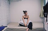 The author Lyn Chen sitting on her bed in her new rented room in Suginami City, Japan