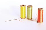 A trio of spools of thread, one yellow, one green and one red