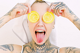 Free and unrecognizable happy woman with tongue out and lemon slices held over eyes.