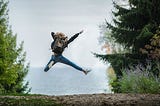 Woman jumping out of celebration on an open trail.