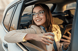 A smiley beautiful girl wearing glasses having a cup in one hand and mobile in another hand traveling and exploring Perth with Maxi Taxi Services