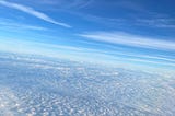 looking down onto a blanket of clouds with a blue sky above it
