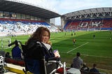 Alex in wheelchair smiling in front of pitch