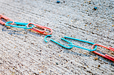 Turquoise and coral paperclip chain broken in the center.