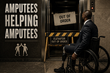 Man in a wheelchair with a prosthetic leg faces an “Out of Order” elevator. Wall reads “Amputees Helping Amputees.” Indoor setting.