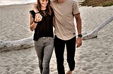 happy couple walking along beach holding hands