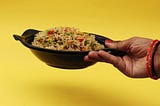 Woman’s hand holding a bowl of fried rice