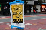 A poster attached to a street sign reads Break Free from Fossil Fuels.