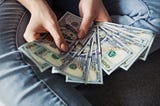 A person holding 100 US Dollar banknotes