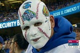 A Dodger fan at a Dodger game with his face painted as a baseball and “Viva Los Dodgers” printed on his forehead.