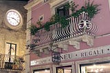 Image of a clock face in a beautiful Italian village. A privileged environment where billionaires buy expensive watches. Photo by Belcairn (author)
