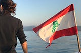 The author on a boat with a Lebanese flag, staring into the distance