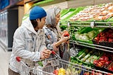 Man and a woman shopping in a grocery store looking at fresh vegetables
